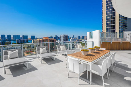 Chic rooftop terrace with dining area overlooking a city skyline.