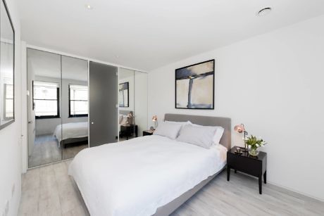 Sleek bedroom with mirrored closet doors and minimal decor.