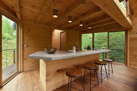 Wooden cabin interior with large windows and a kitchen counter.