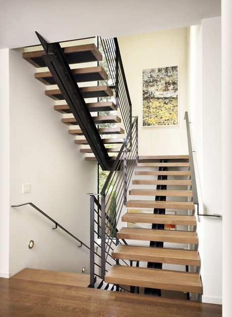 Contemporary floating staircase with metal railings and wooden steps.