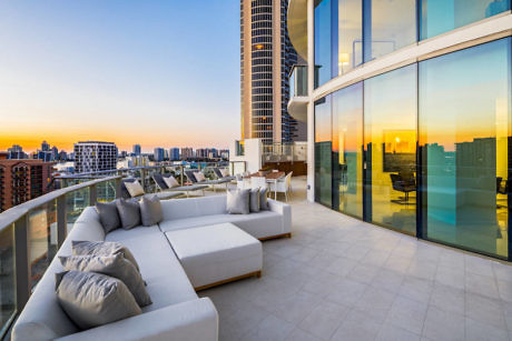 Chic rooftop terrace with plush sofas and a city skyline view at sunset.