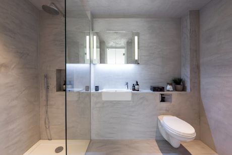 Contemporary bathroom with marble finish, glass shower, and sleek fixtures.