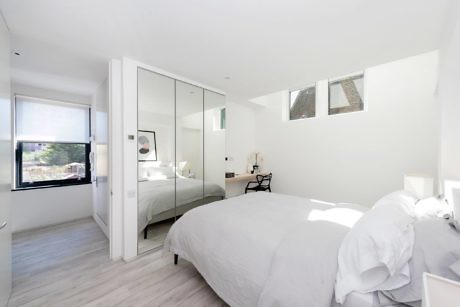 Bright, minimalist bedroom with glass partition and skylights.