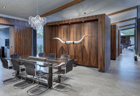 Modern dining room with a glass table, designer chairs, and artistic lighting.