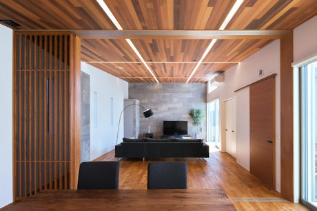 Modern living room with wooden floors, ceiling, and a black sofa.