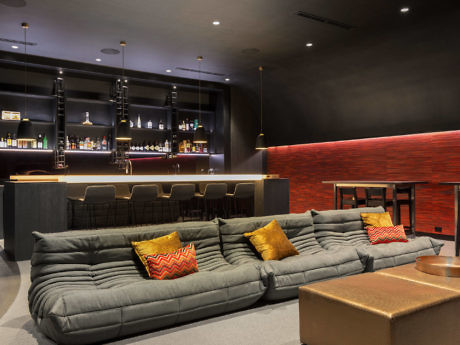 Chic lounge with plush gray sofas, vibrant pillows, and a sleek bar area