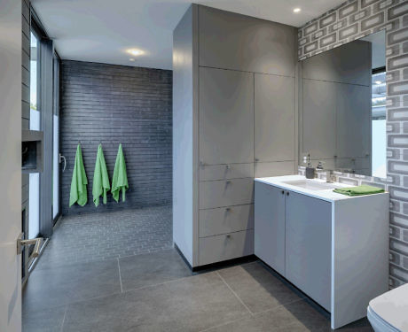 Contemporary bathroom with sleek grey cabinetry and green towels.