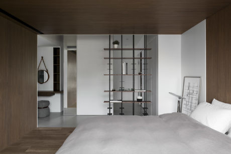 Minimalist bedroom with wood paneling and shelving unit divider.