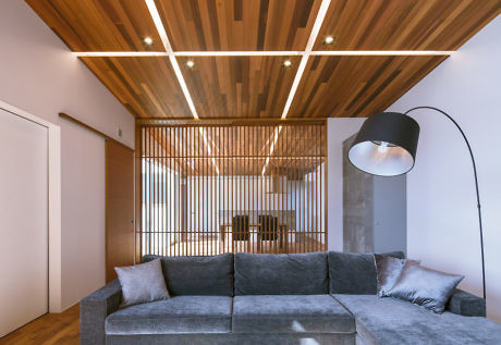 Contemporary living room with wooden slatted ceiling and oversized floor lamp.