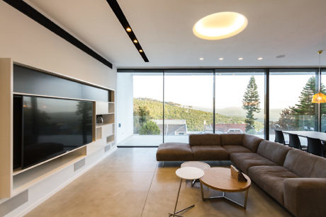 Modern living room with large TV and floor-to-ceiling windows.
