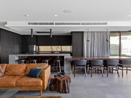 Modern living room with kitchen, dining area, and leather sofa.