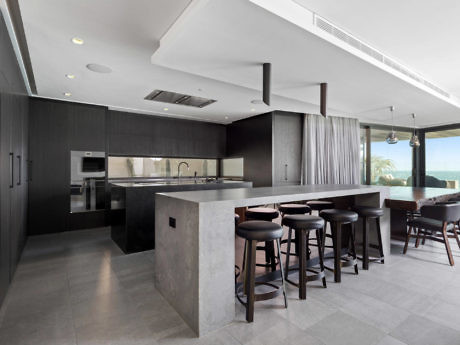 Minimalist kitchen with concrete island and ocean view.