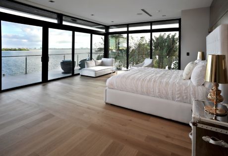 Modern bedroom with large windows overlooking a body of water.