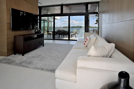 Contemporary living room with large windows overlooking a waterfront.