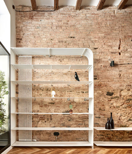 Modern white shelving unit against a rustic exposed brick wall in a room with h