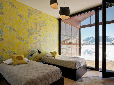 Contemporary bedroom with vibrant yellow wallpaper and snowy mountain view.