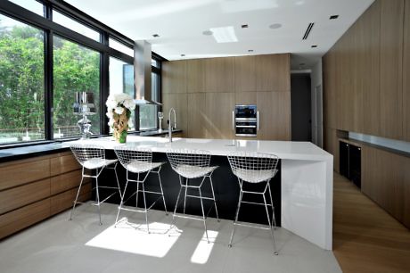 Modern kitchen with wooden cabinets, white island, and wire chairs.