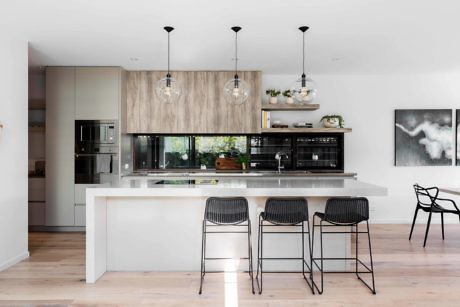 Sleek kitchen with wood accents, island bar, and pendant lights.