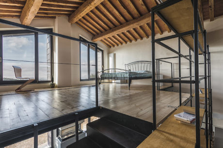 Modern interior with exposed beams, large windows, and a mezzanine level.