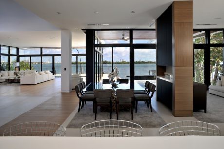 Modern dining area with lake view, open-plan layout, and elegant furniture.