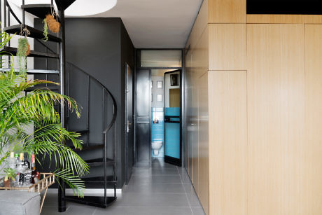 Modern hallway with black spiral staircase and light wooden cabinets.