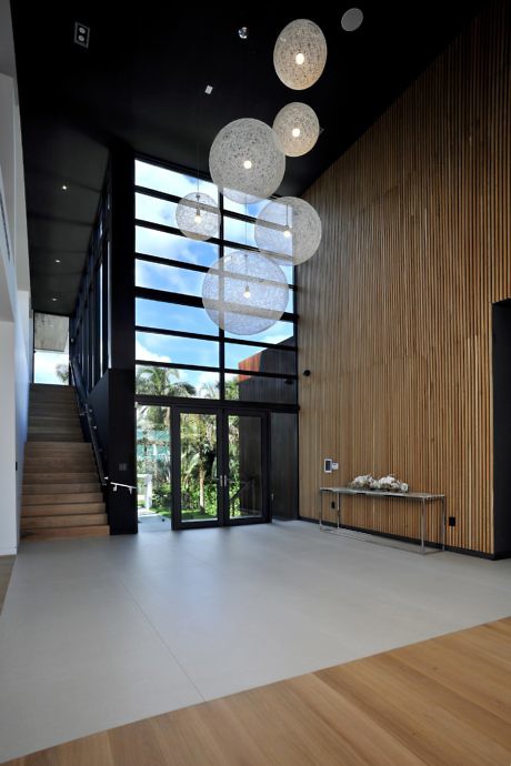 Contemporary foyer with orb lights, wooden walls, and tall windows.