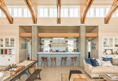 Modern kitchen in an open-plan living space with high ceilings and wooden details.