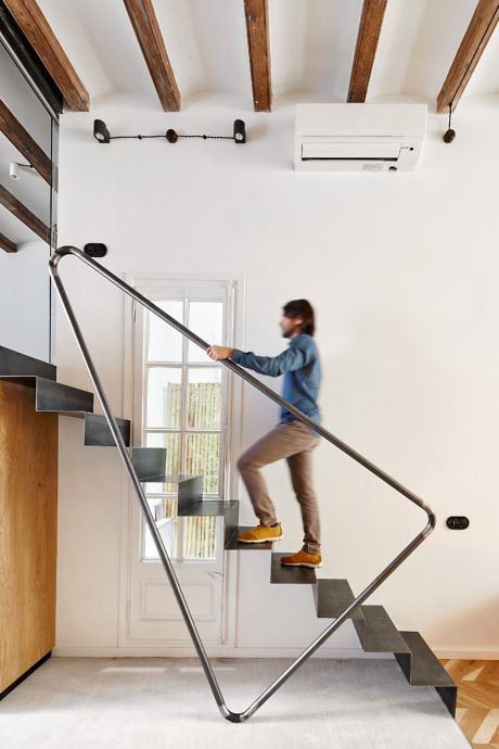 Minimalist stairway with a geometric design in a room with exposed wooden beams.