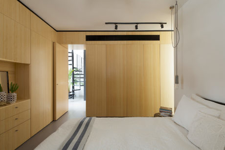 Minimalist bedroom with light wood sliding doors and built-in cabinetry.