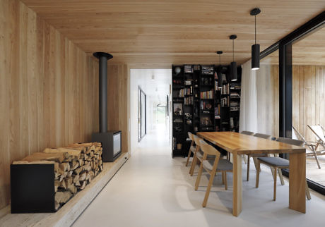 Minimalist interior with wooden walls, a long table, and black shelving.