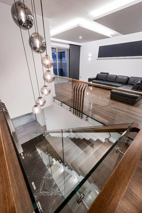 Contemporary living room with glass balustrade and unique pendant lights.