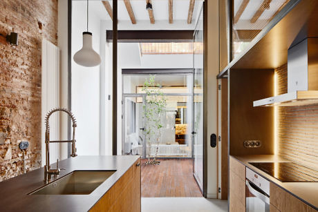 Contemporary kitchen with exposed beams and brick wall.