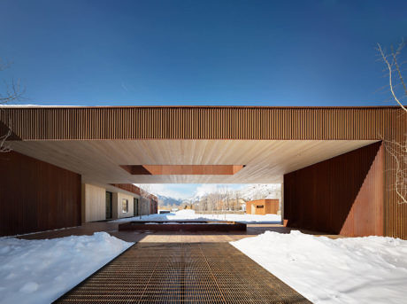 Modern wood-panelled building with a covered walkway and snow.