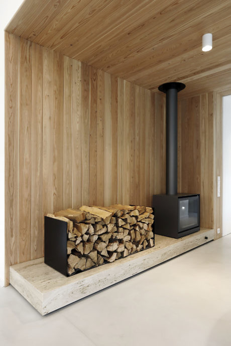 Contemporary wood-paneled nook with fireplace and stacked logs.