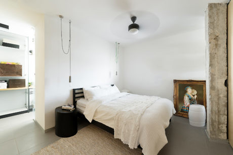 Modern minimalist bedroom with white bedding and exposed concrete.
