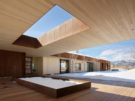 Modern wooden building with large windows and snow-covered courtyard.