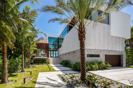 Modern house with large windows surrounded by palm trees.