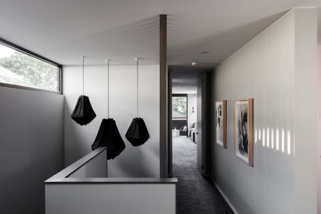 Minimalist hallway with pendant lights and art display.