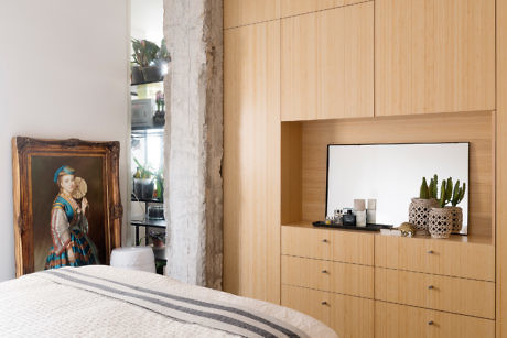 Contemporary bedroom with wooden built-in closet and vintage painting.