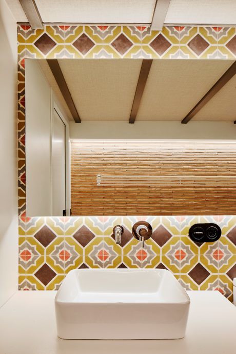A modern bathroom with a patterned backsplash and square sink.