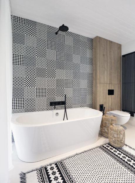 Contemporary bathroom with geometric tiled wall, freestanding tub, and wooden accents