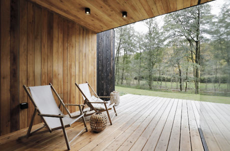 Wooden deck with two chairs facing nature view.