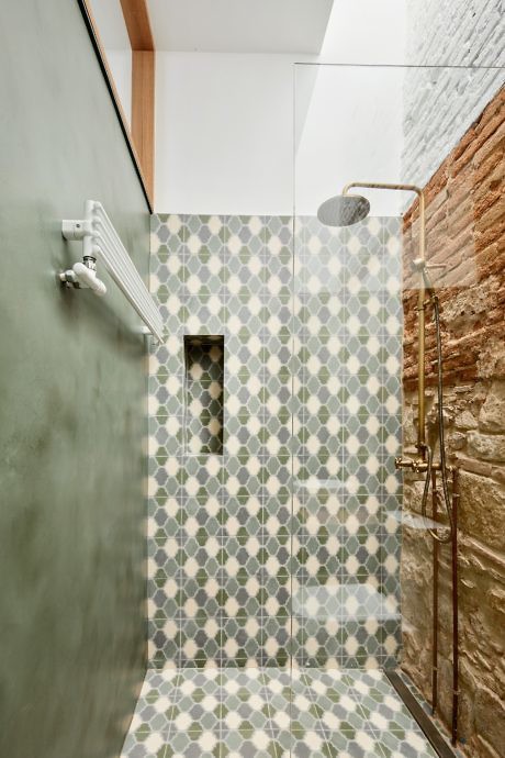 Contemporary shower with patterned tiles and exposed brick wall.