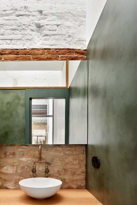 Modern bathroom with exposed stone and brick walls, metal tap, and vessel sink.