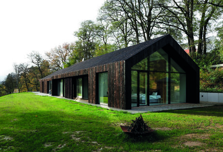 Contemporary house with large glass windows and wooden exterior.