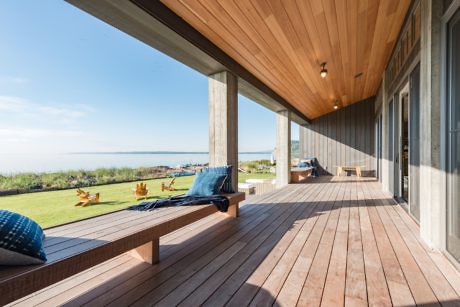 Spacious wooden deck with ocean view and outdoor seating.