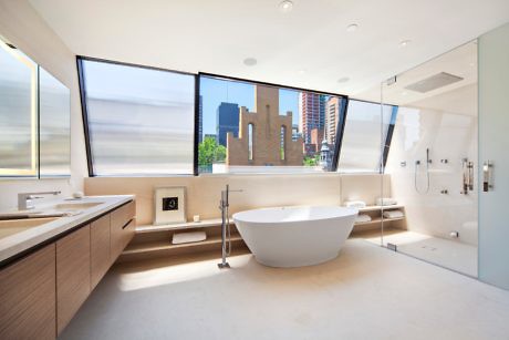 Modern bathroom with a freestanding tub and city view through large windows.