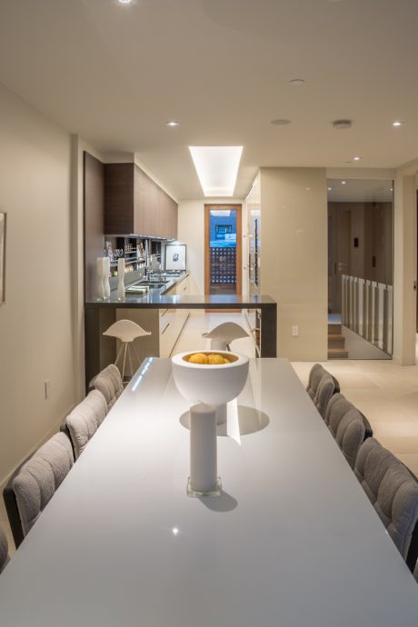 Modern kitchen interior with long dining table and pendant lights.