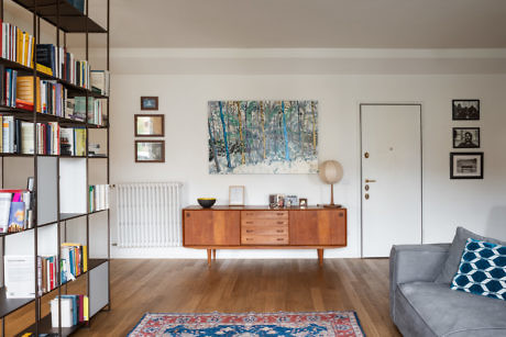 Modern living room with bookshelf, mid-century sideboard, and grey sofa.