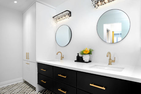 Chic bathroom with black vanity, gold fixtures, and patterned floor.
